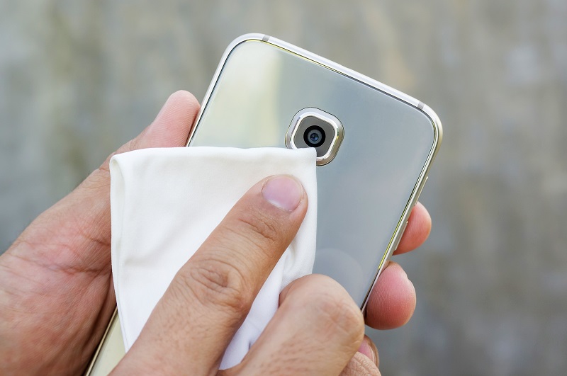 Membersihkan lensa kamera HP dengan kain mikrofiber